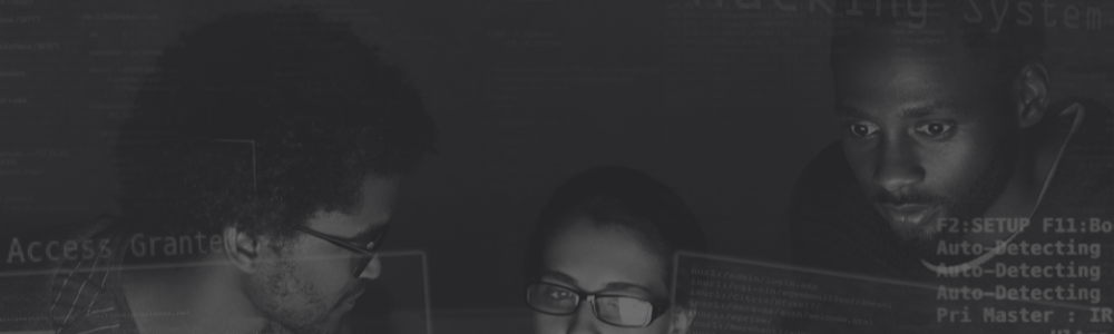 Foto em preto e branco de 3 pessoas olhando para um monitor